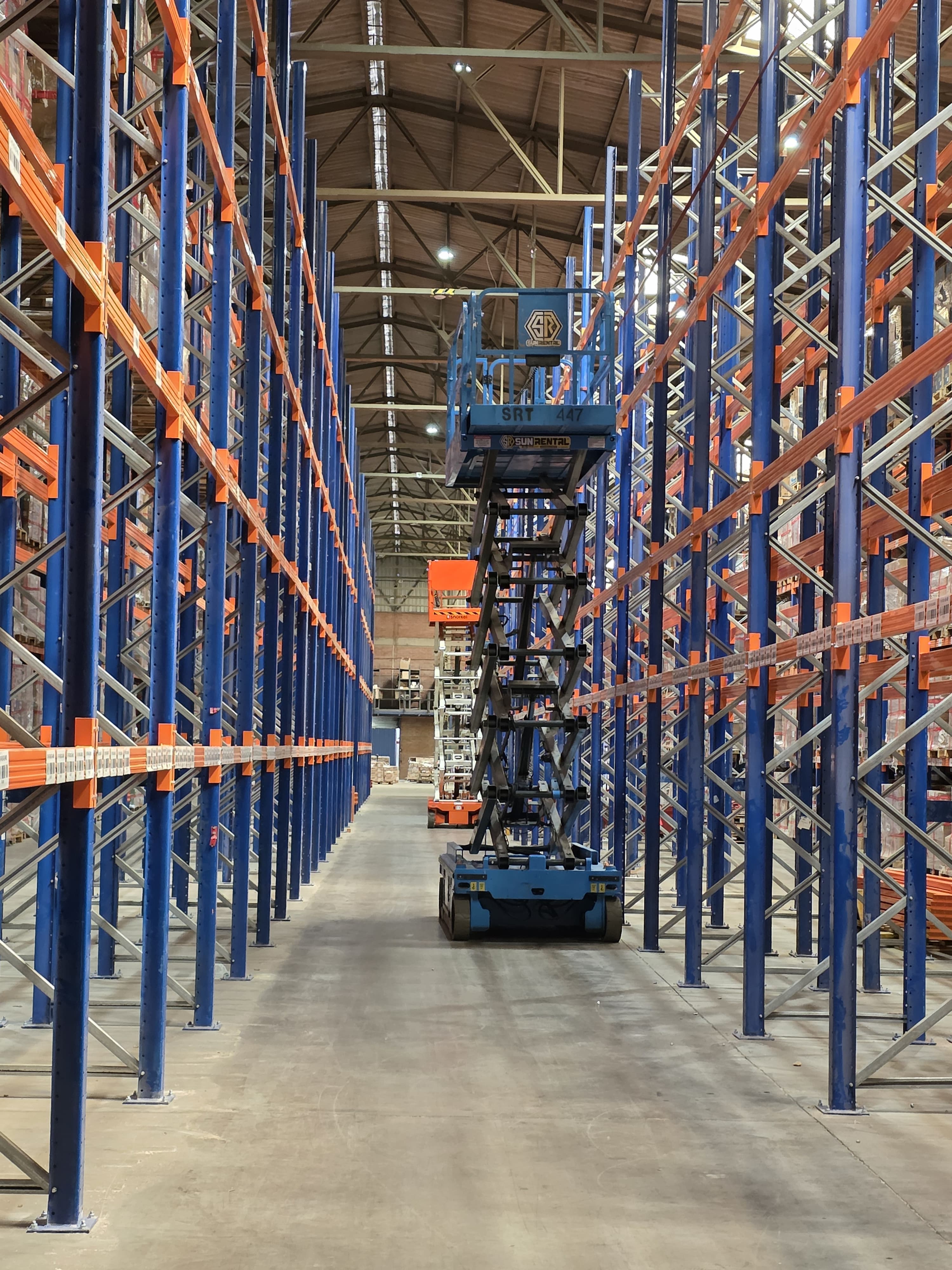 Bodega industrial de gran altura con racks metálicos y pallets almacenados